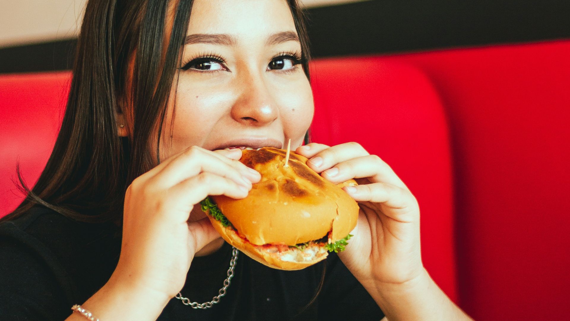 woman in black long sleeve shirt eating burger
