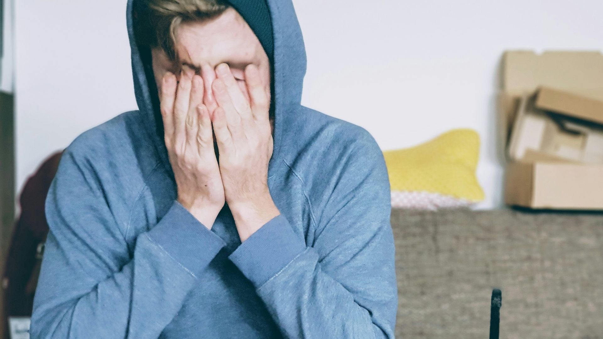 man covering face with both hands while sitting on bench