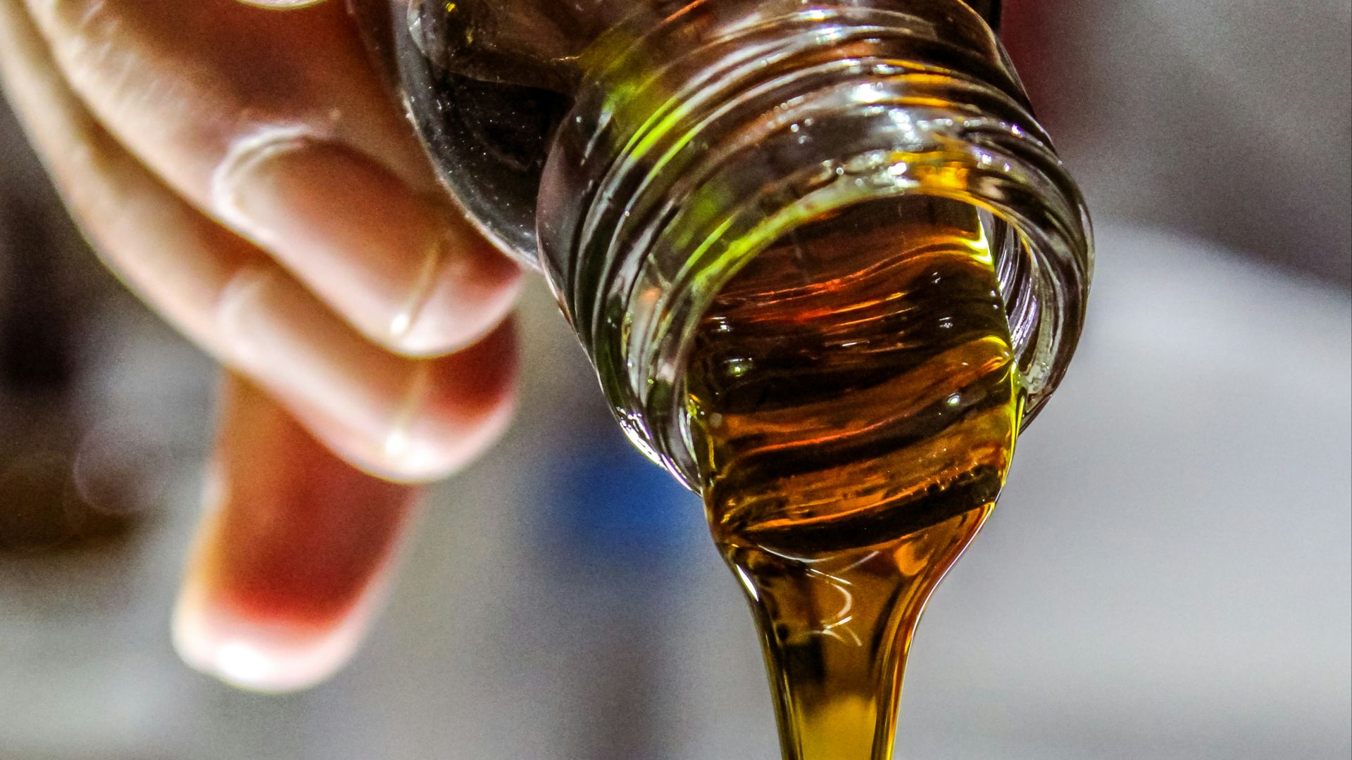 person holding clear drinking glass with brown liquid