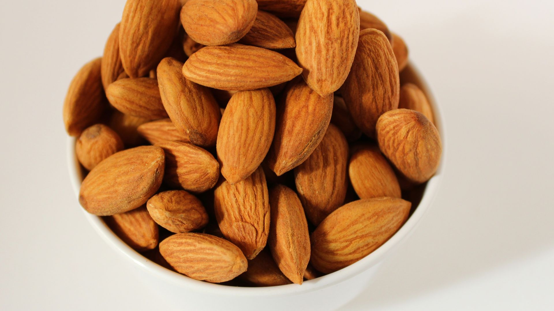 brown almond nuts on white ceramic bowl