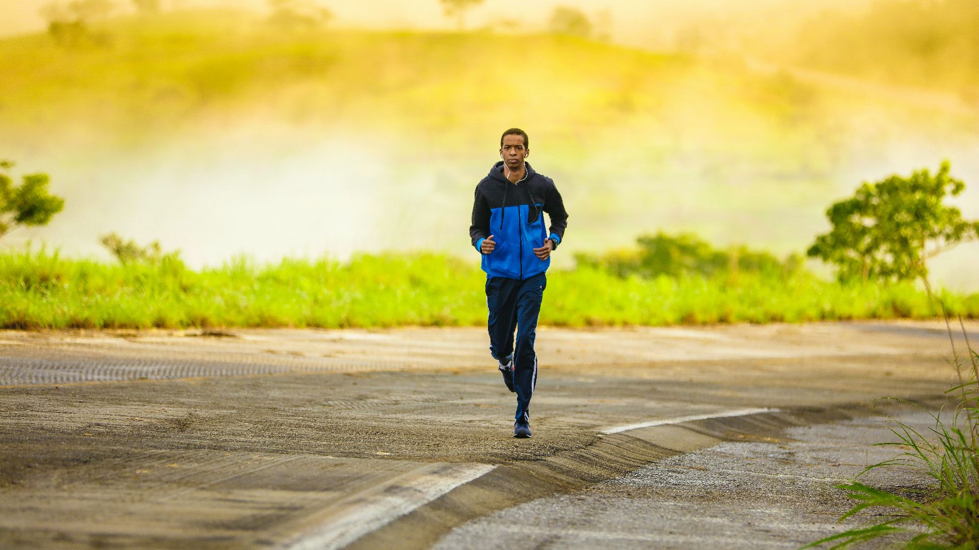 man in track suit jogging on concrete road