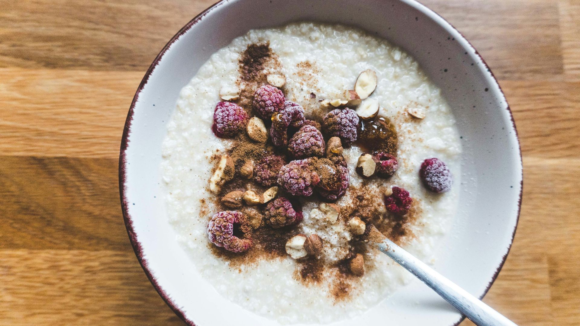 a bowl of oatmeal topped with raspberries and nuts