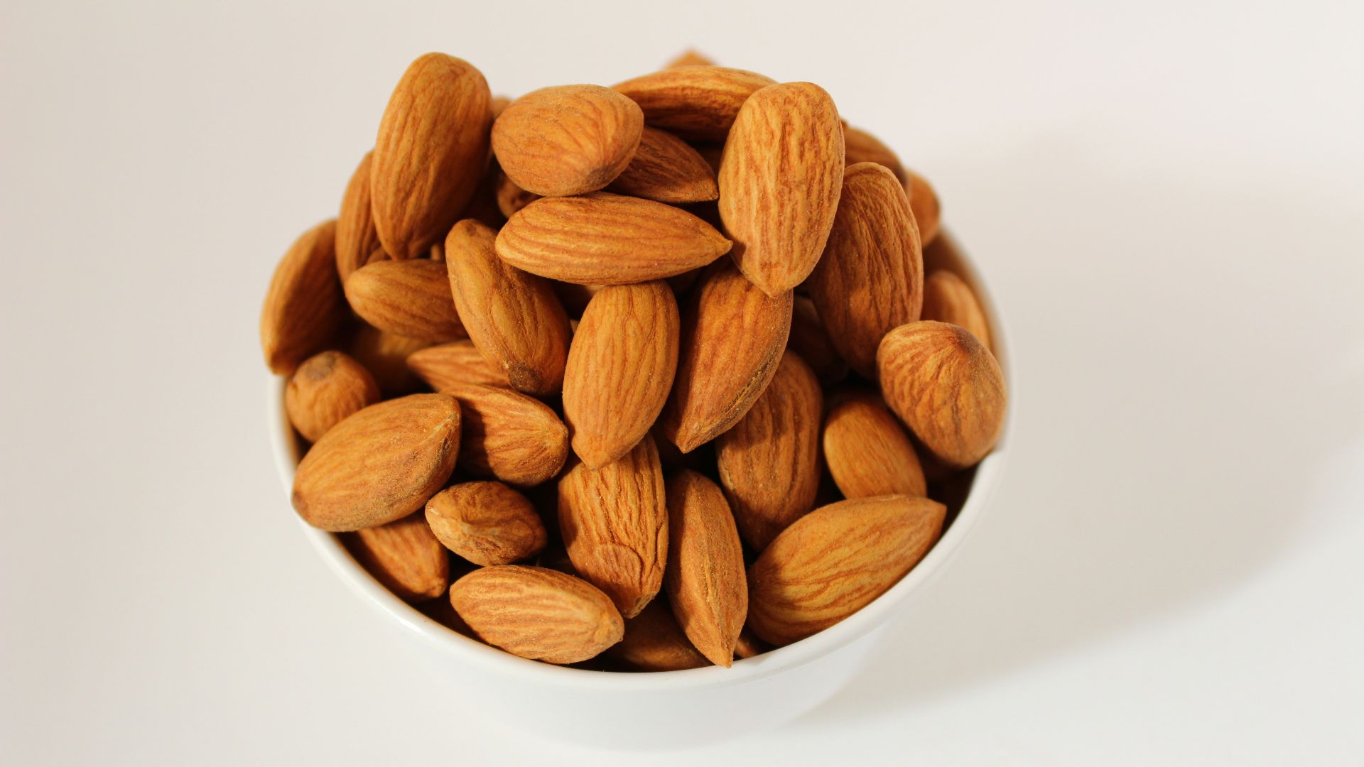 brown almond nuts on white ceramic bowl