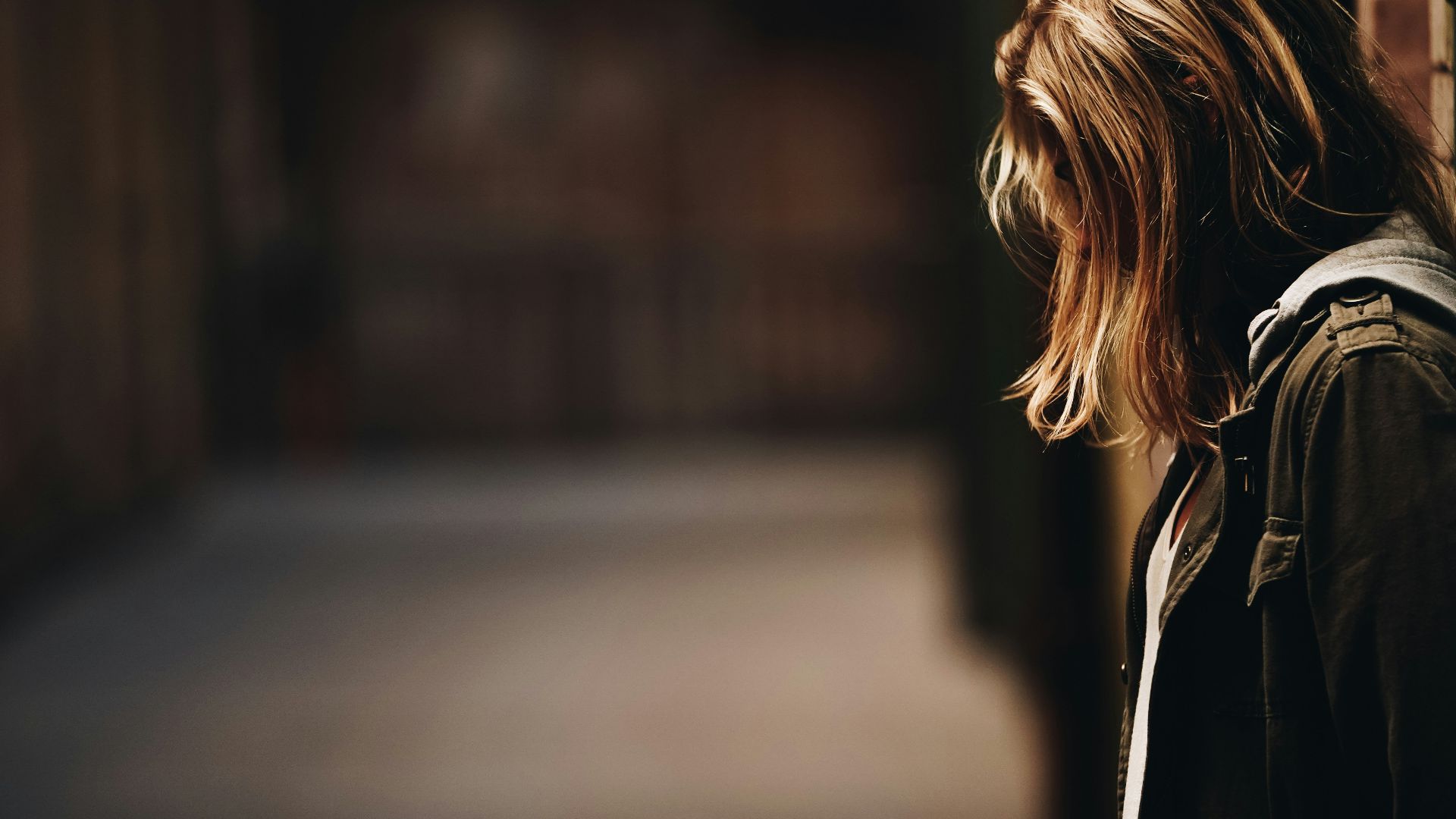 woman leaning against a wall in dim hallway