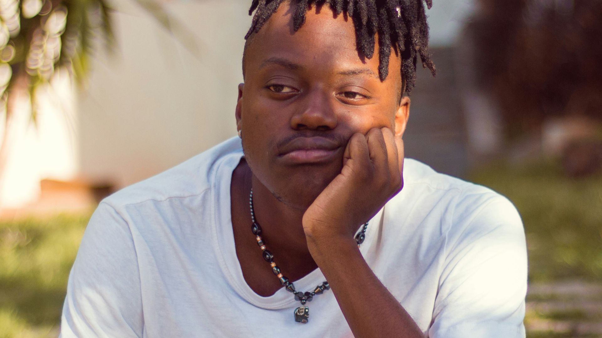 man in white crew neck t-shirt sitting on brown wooden chair