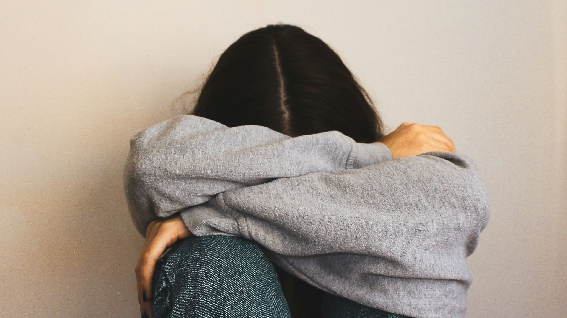 a woman sitting on the floor with her arms wrapped around her head