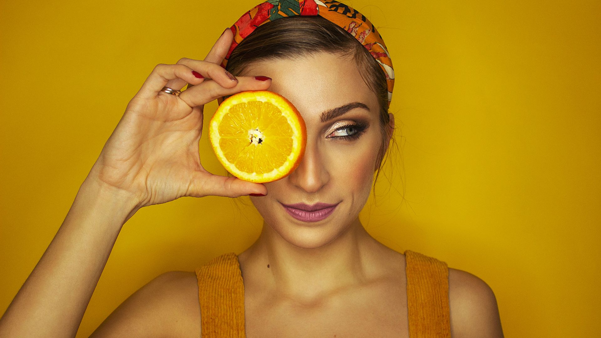 woman covering her right eye with orange slice
