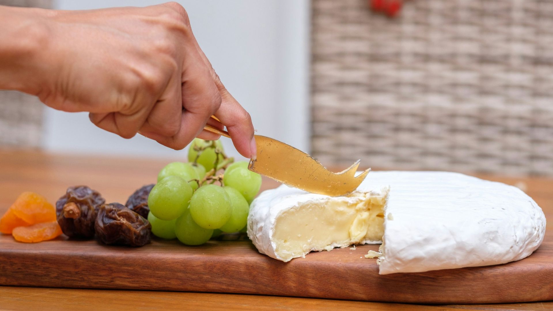 A person cutting a piece of cheese on a cutting board