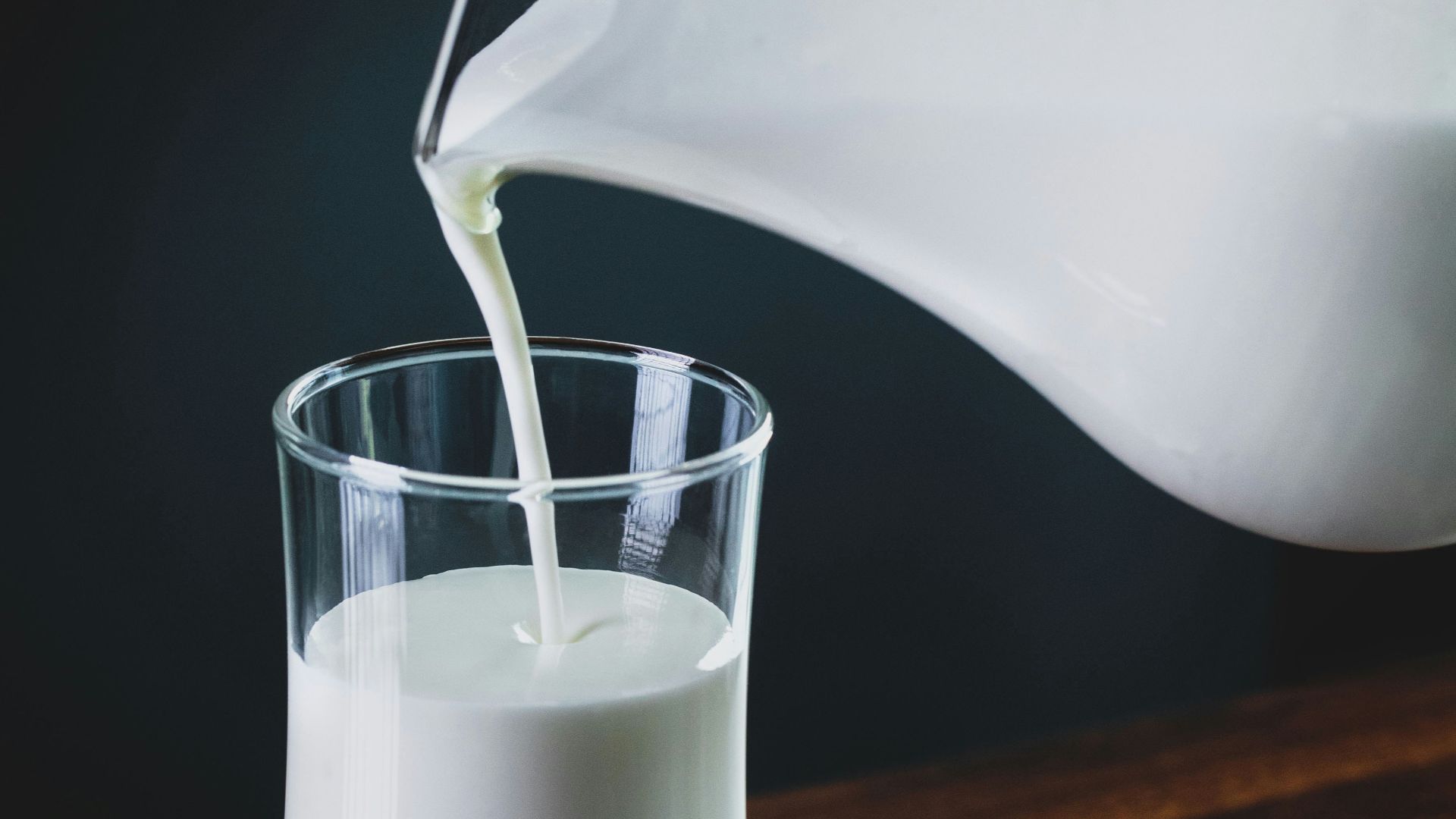 person pours milk into glass