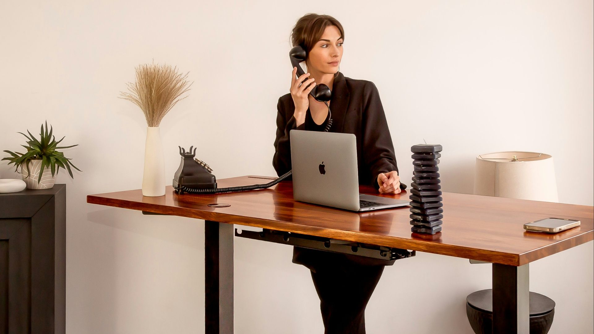 a woman sitting at a desk on a cell phone