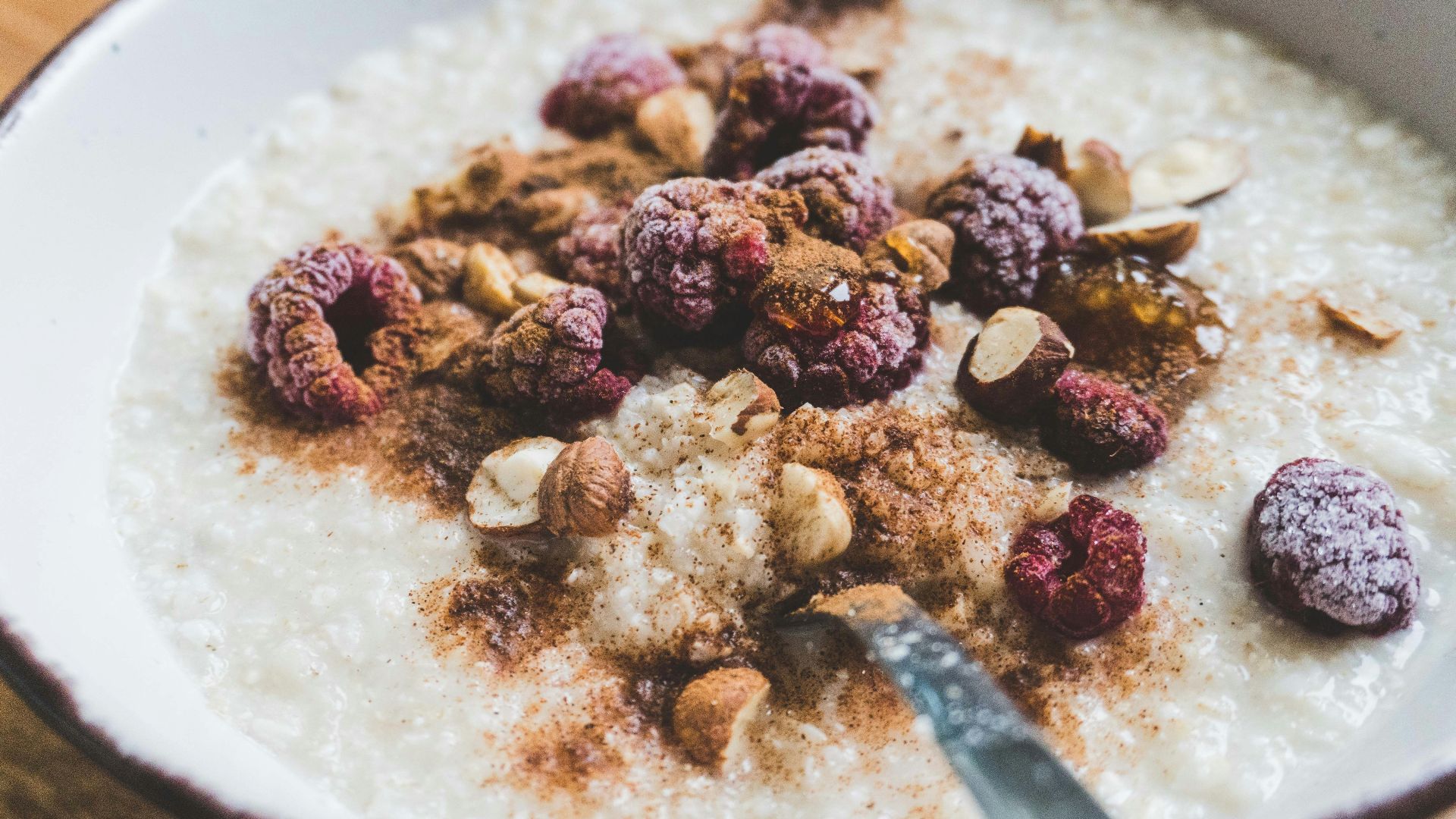 a bowl of oatmeal topped with nuts and raspberries