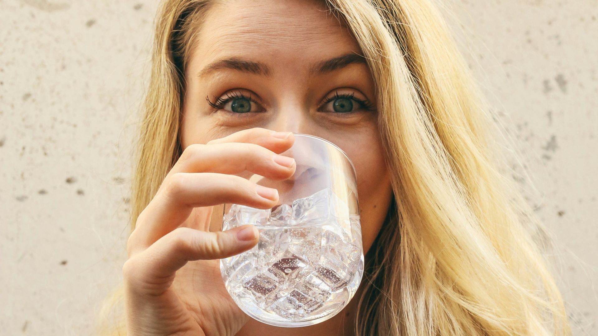 woman in white crew neck shirt drinking water