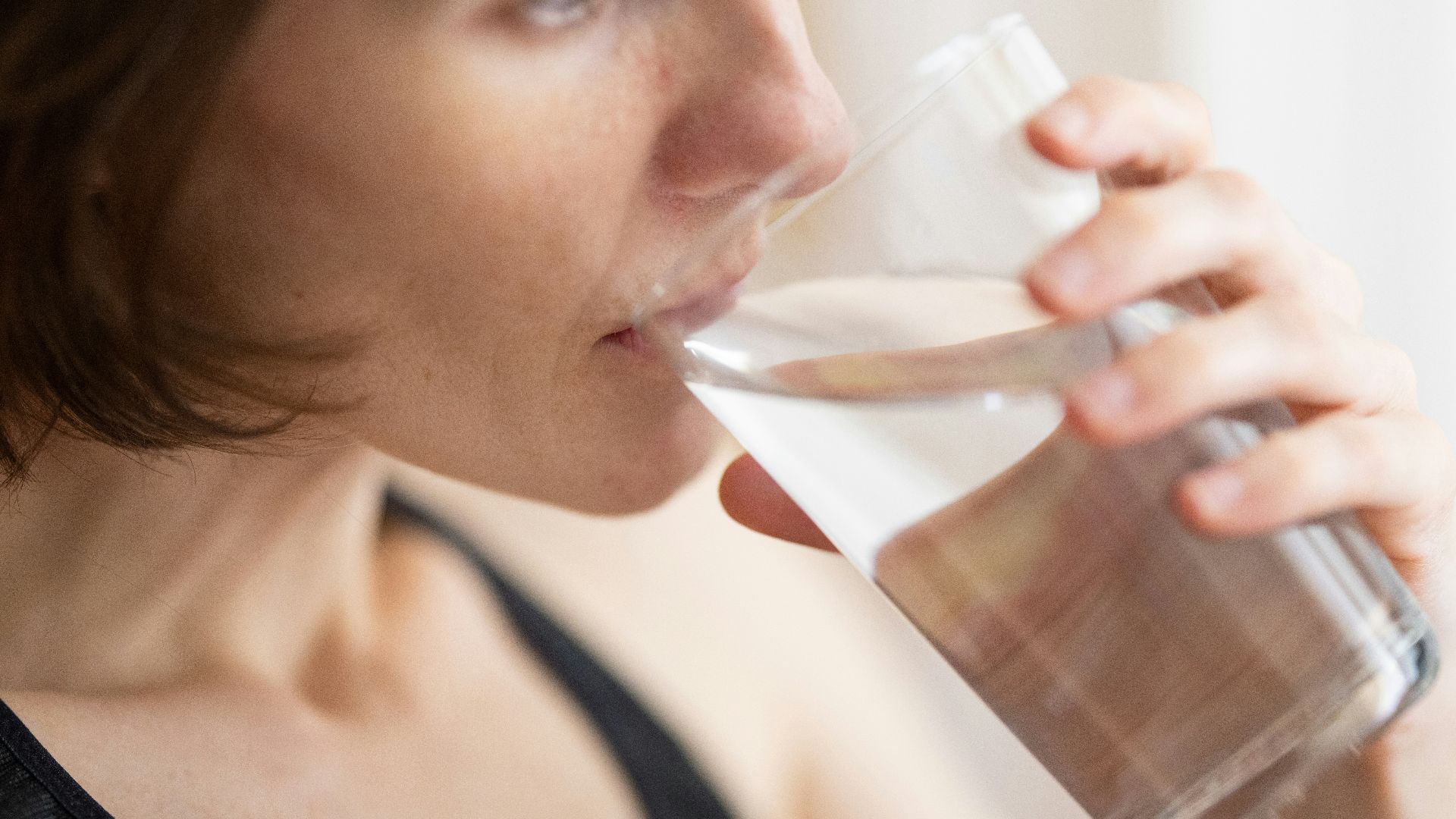 woman in black tank top drinking water