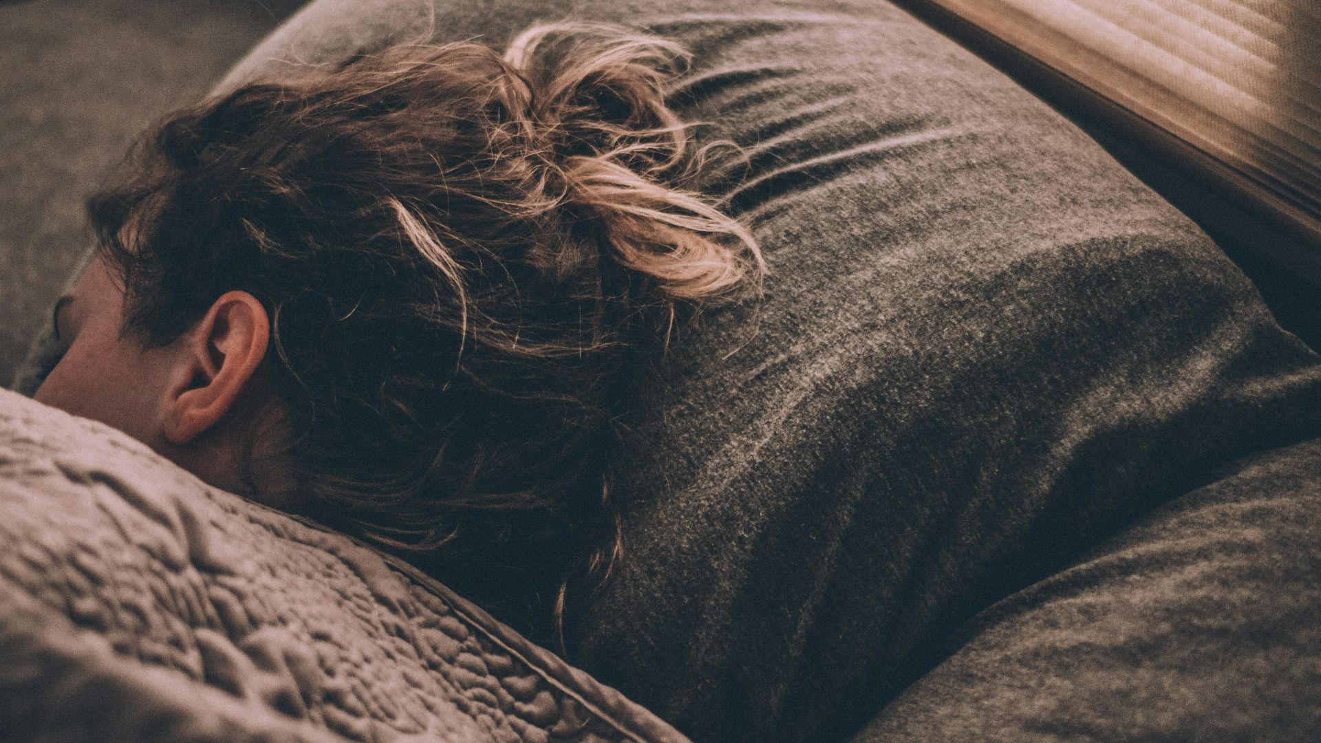 woman sleeping on bed under blankets