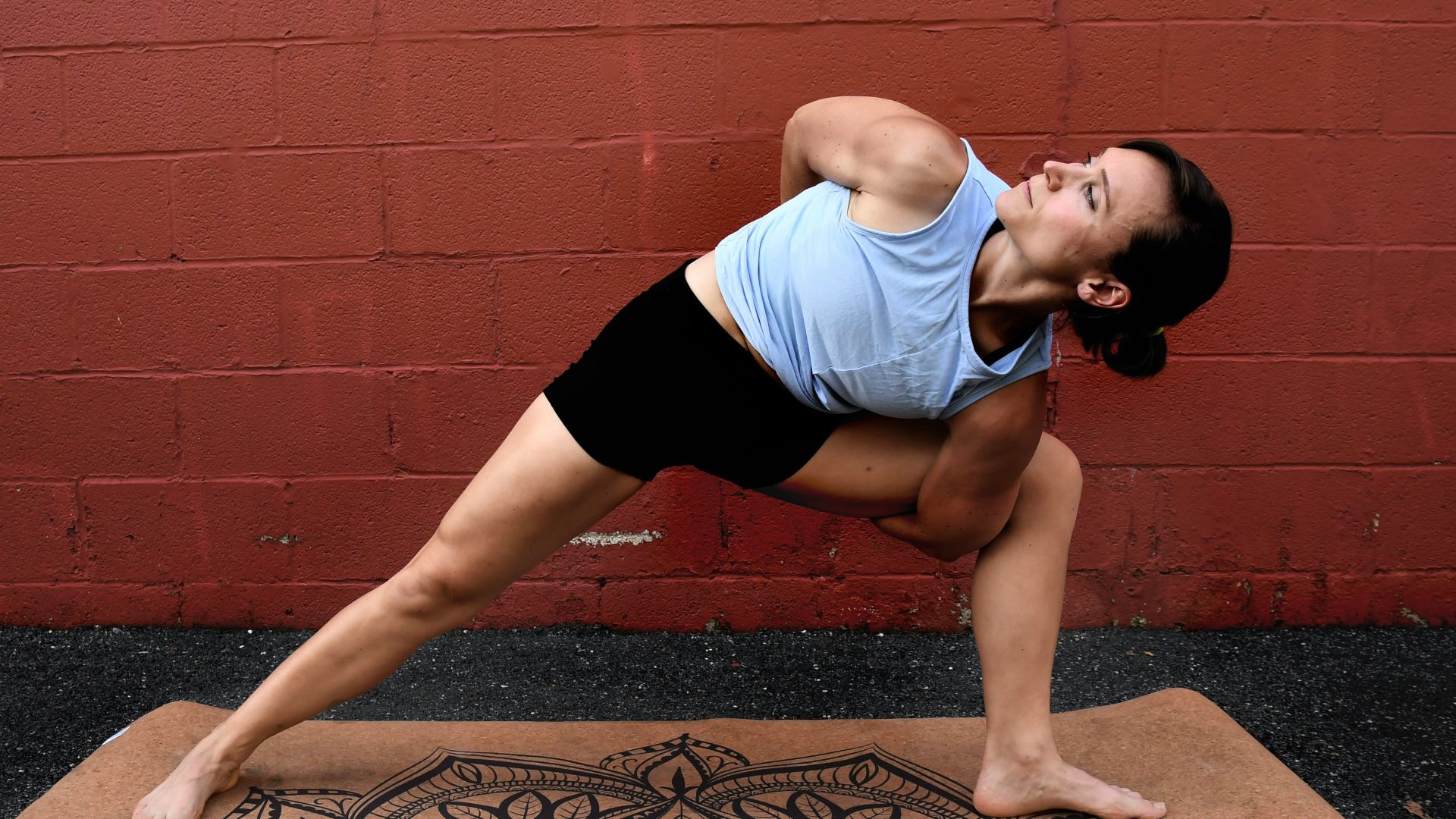 woman in white tank top and black shorts doing yoga on brown concrete floor