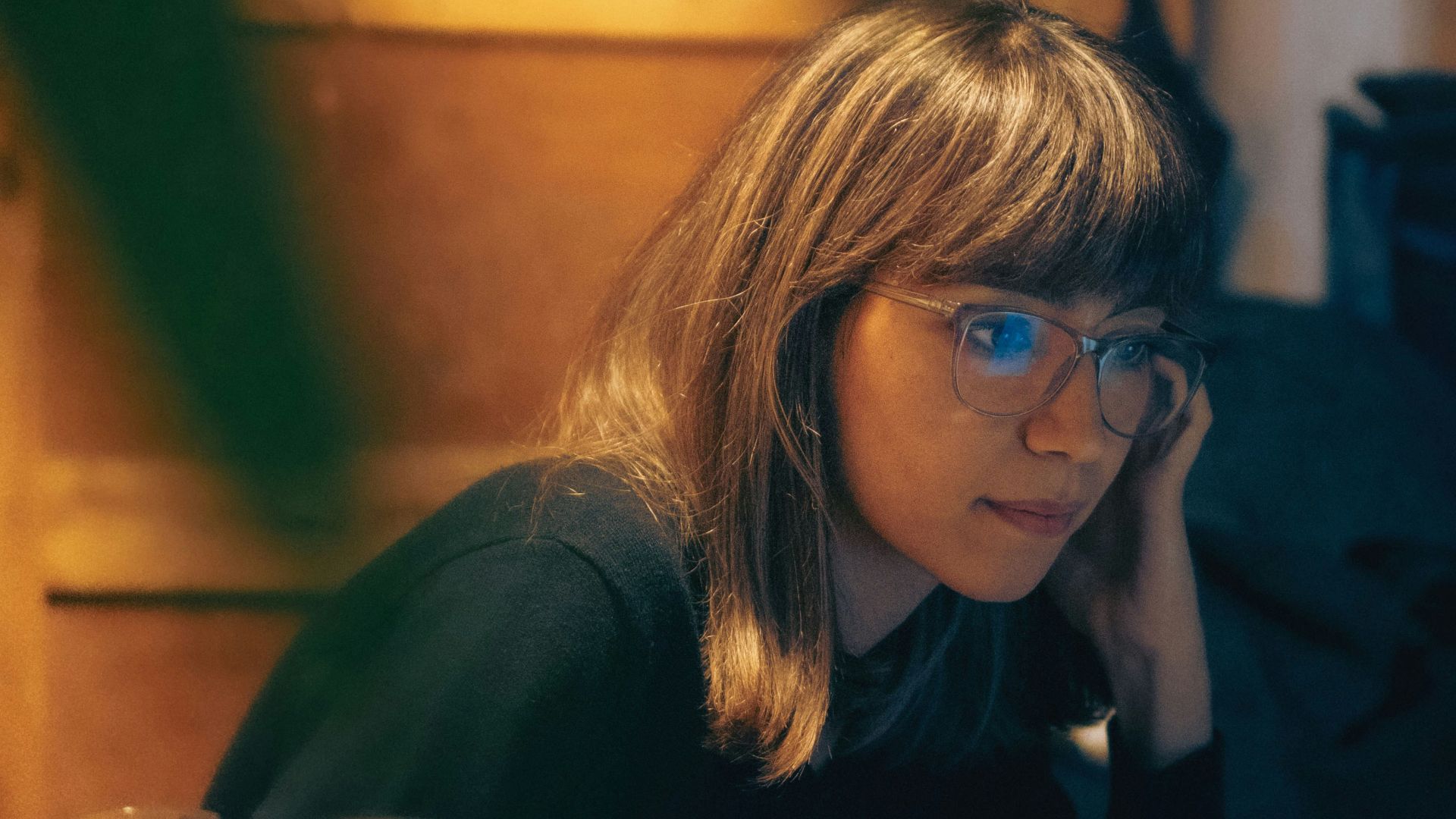 A woman sitting at a table in front of a laptop computer