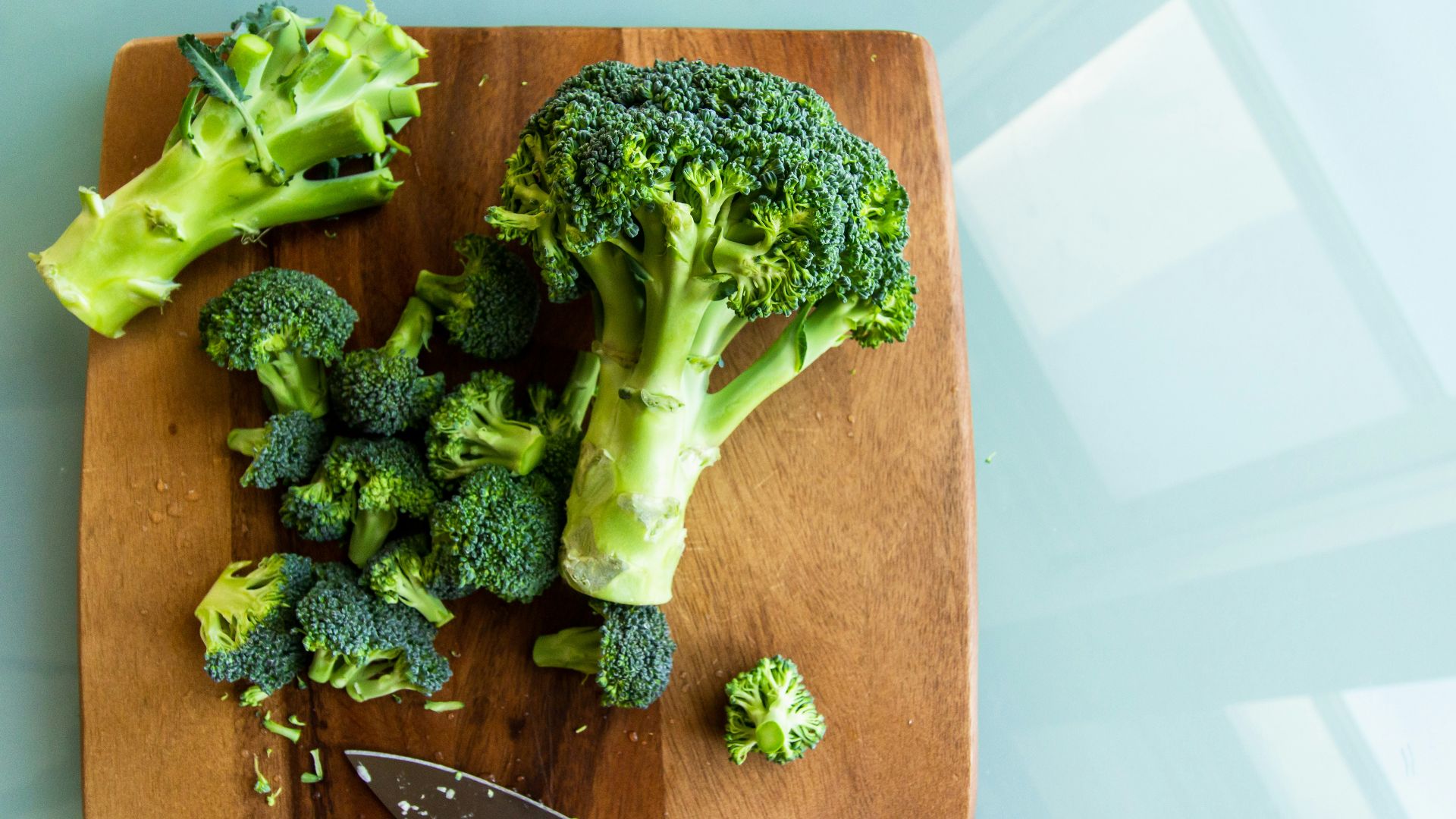 broccoli on brown wooden chopping board