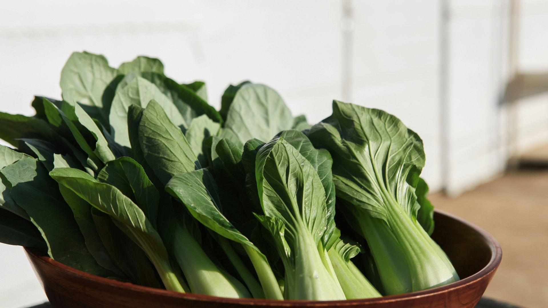 a wooden bowl filled with green leafy vegetables
