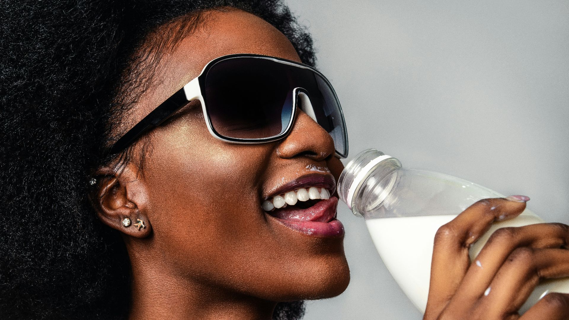 woman wearing black and white sunglasses drinking milk