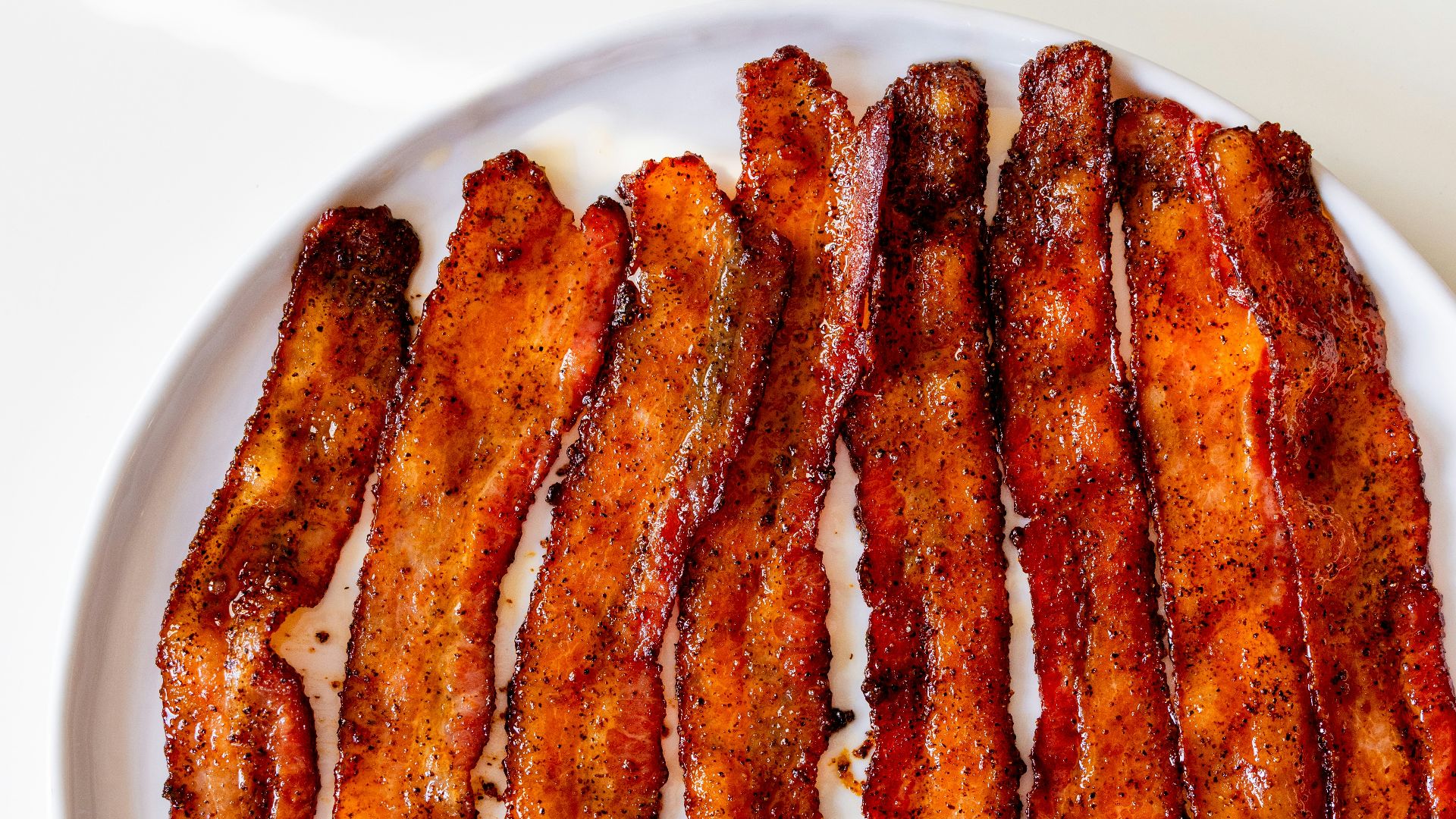 a white plate topped with bacon strips on top of a table