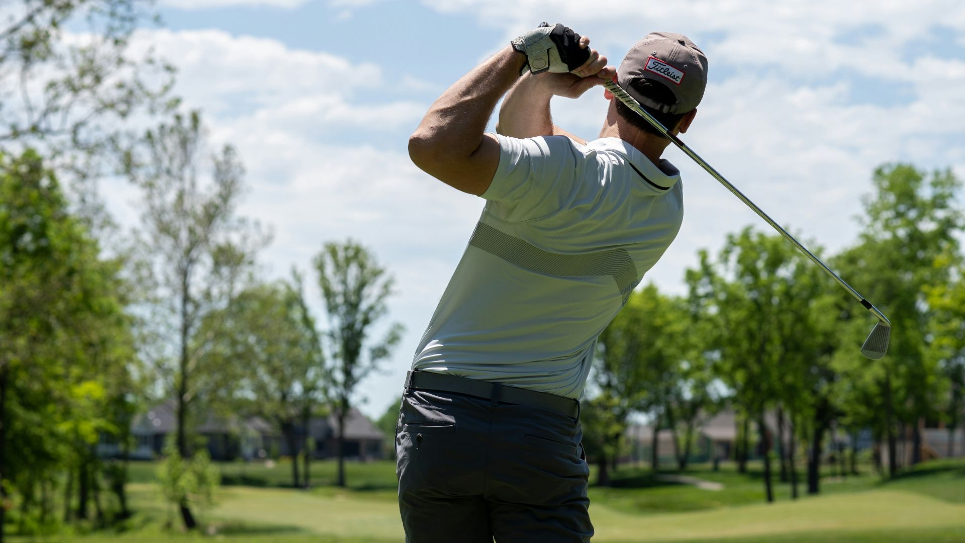 man in white t-shirt and black shorts holding golf club