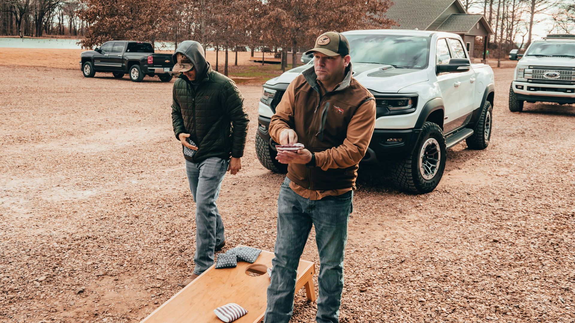 a couple of men standing on a wood board in a dirt field