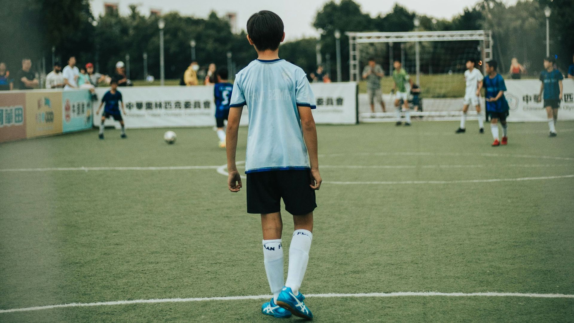 man in white and blue soccer jersey standing on green field during daytime
