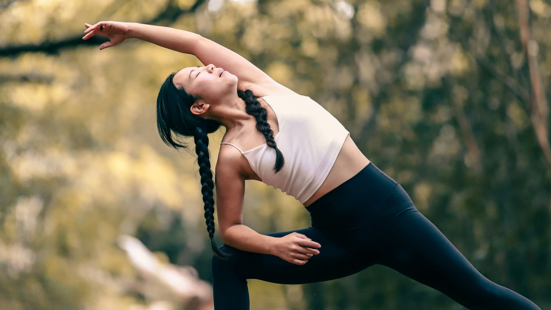 woman in white tank top and black leggings doing yoga during daytime