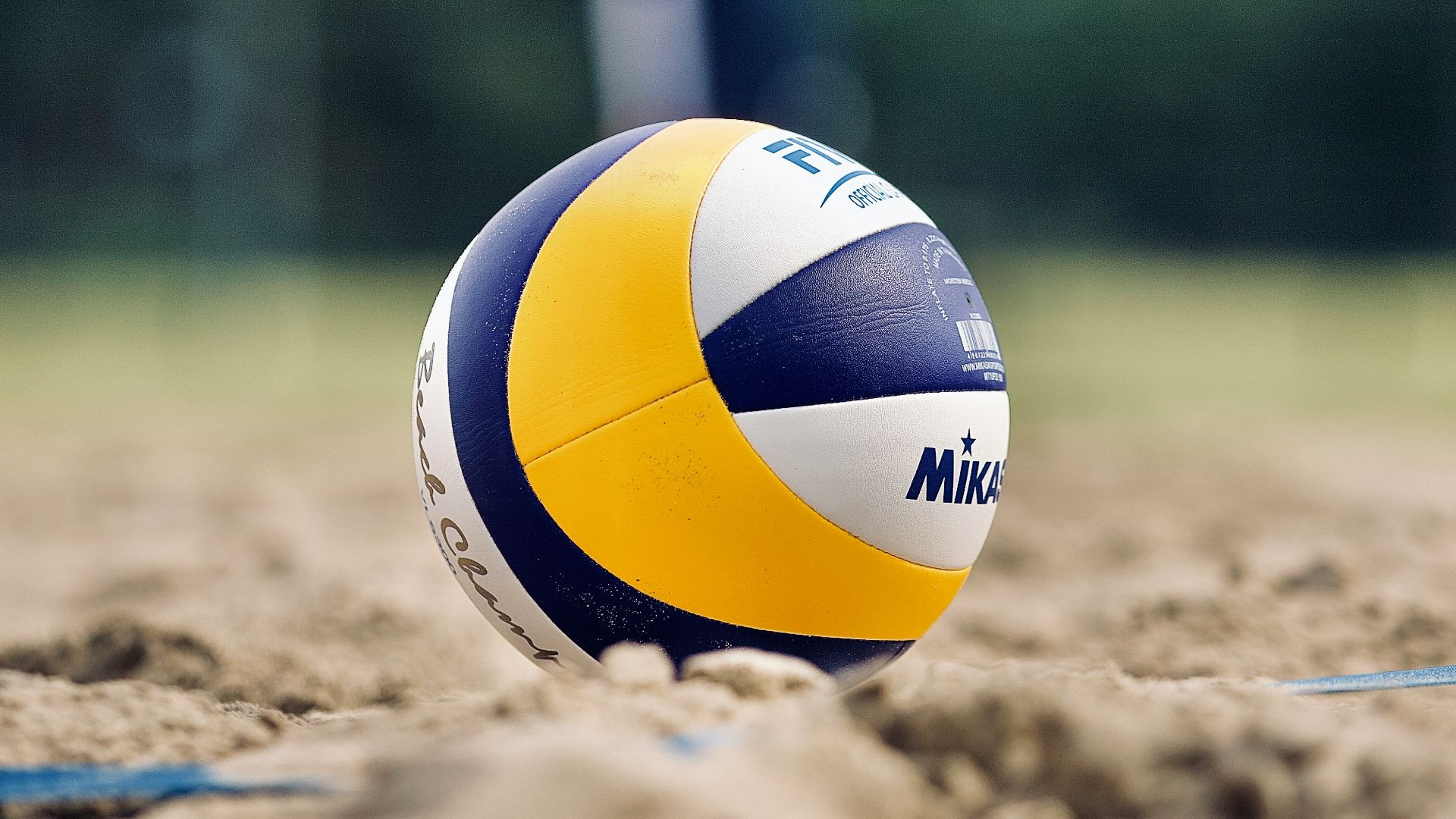 yellow and white volleyball on brown sand during daytime