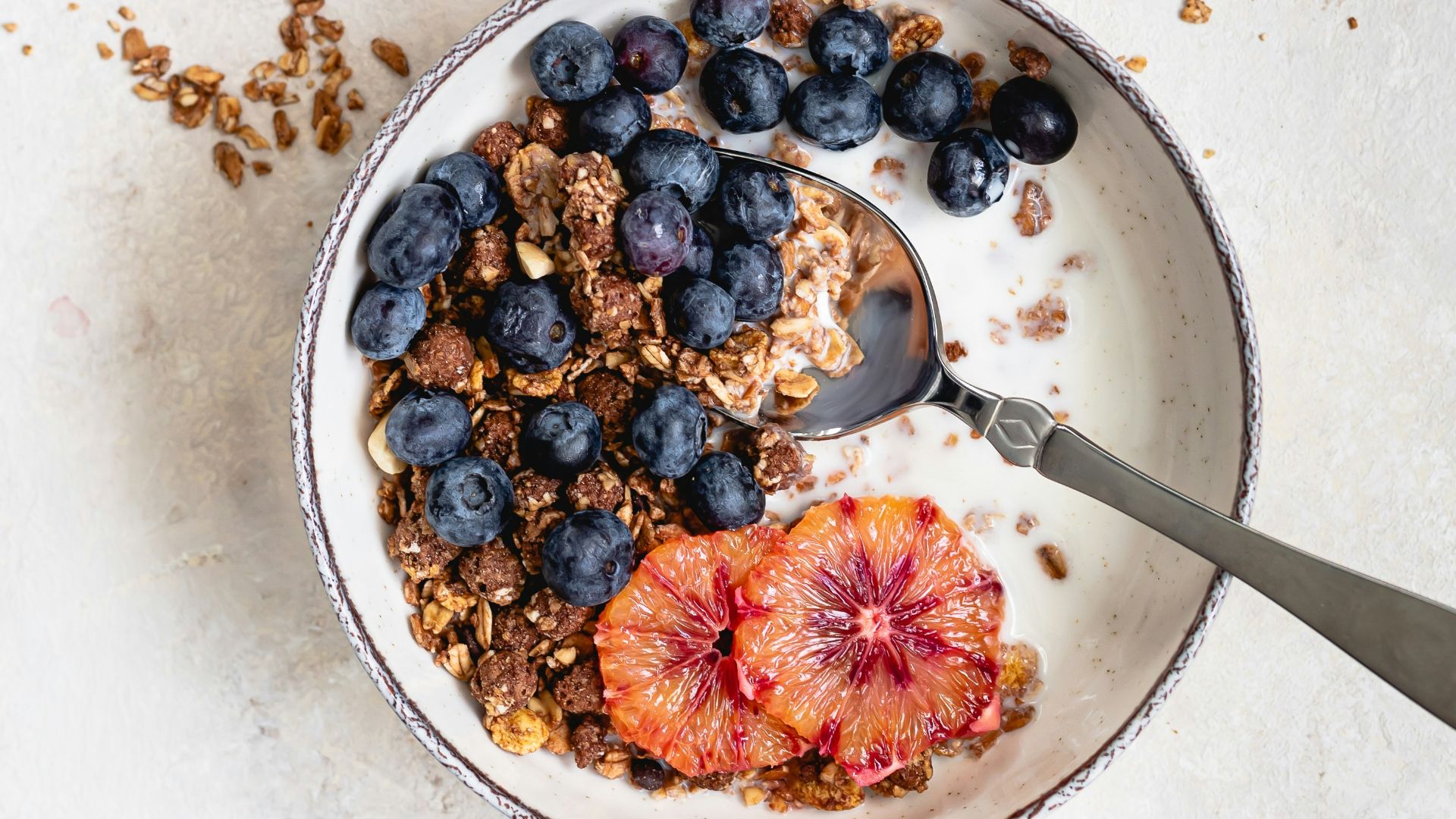 two bowls filled with granola and fruit on top of a table