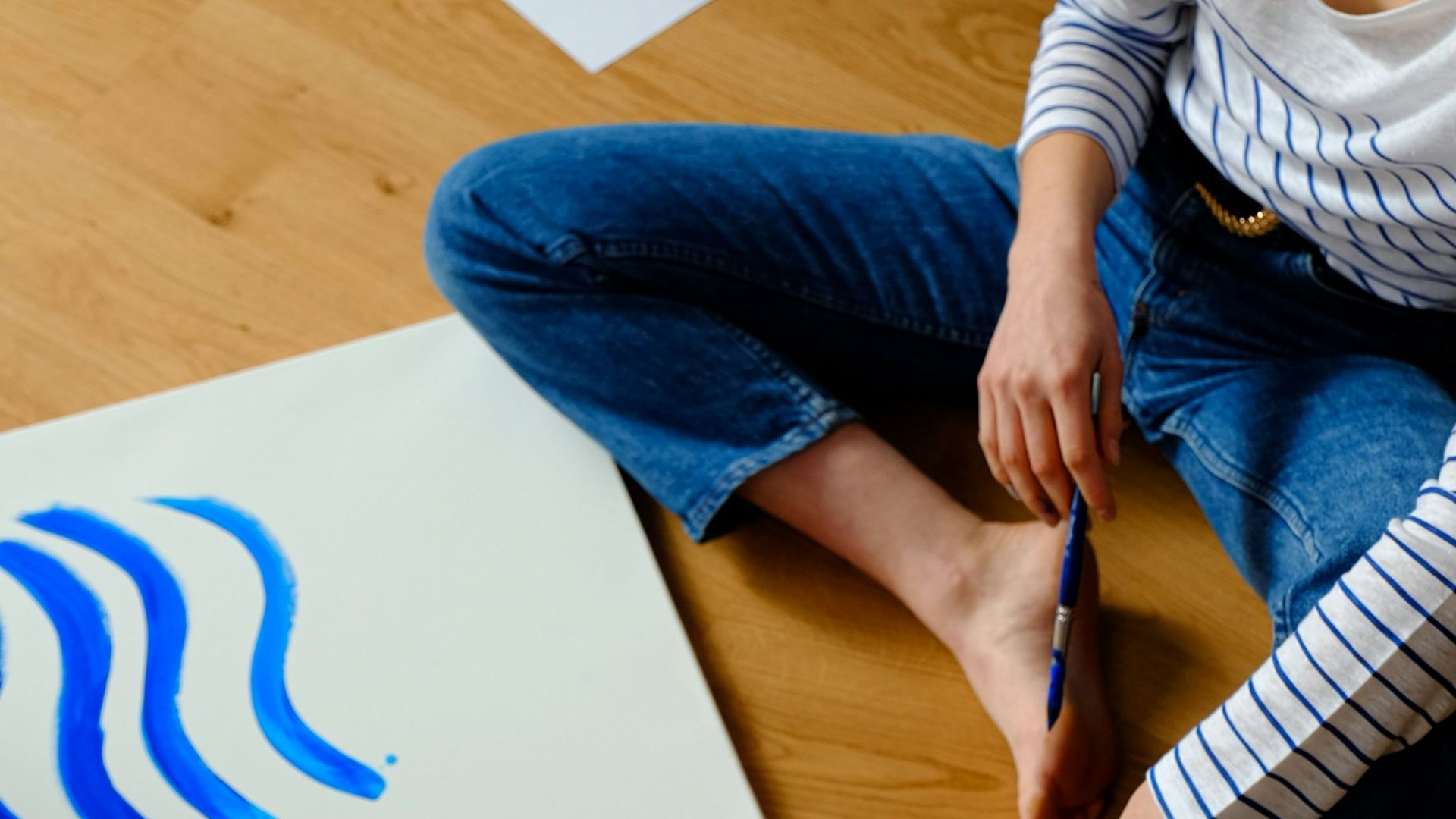woman in white long sleeve shirt and blue denim jeans sitting on brown wooden table