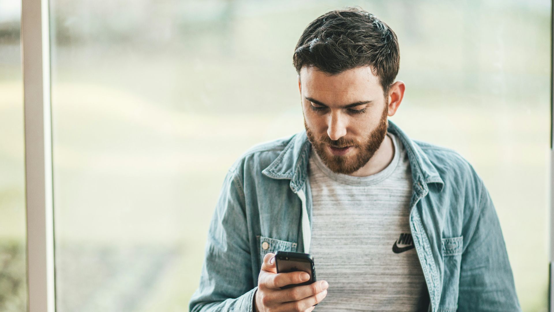man holding a smartphone near the window