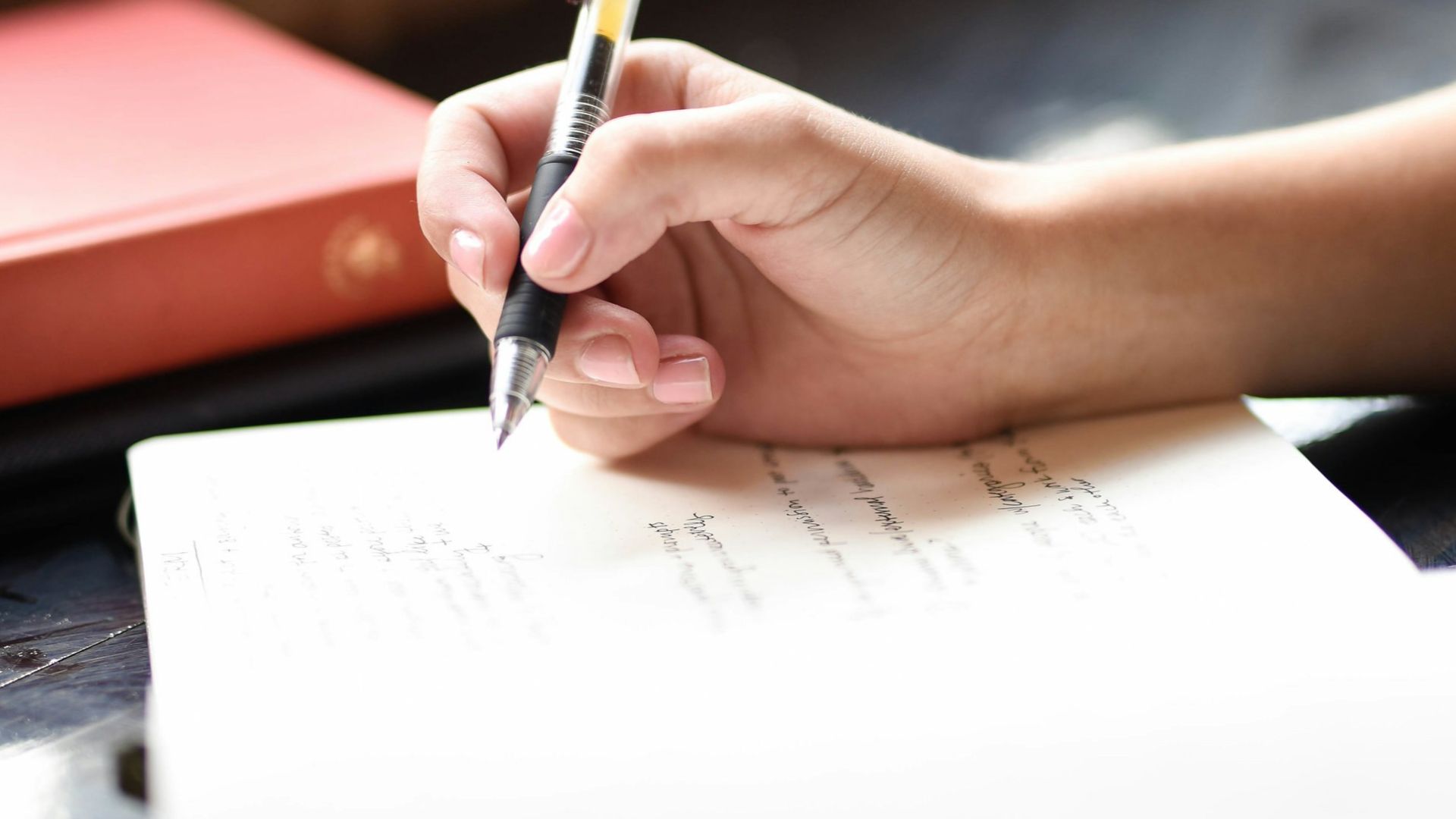 a person writing on a piece of paper with a pen
