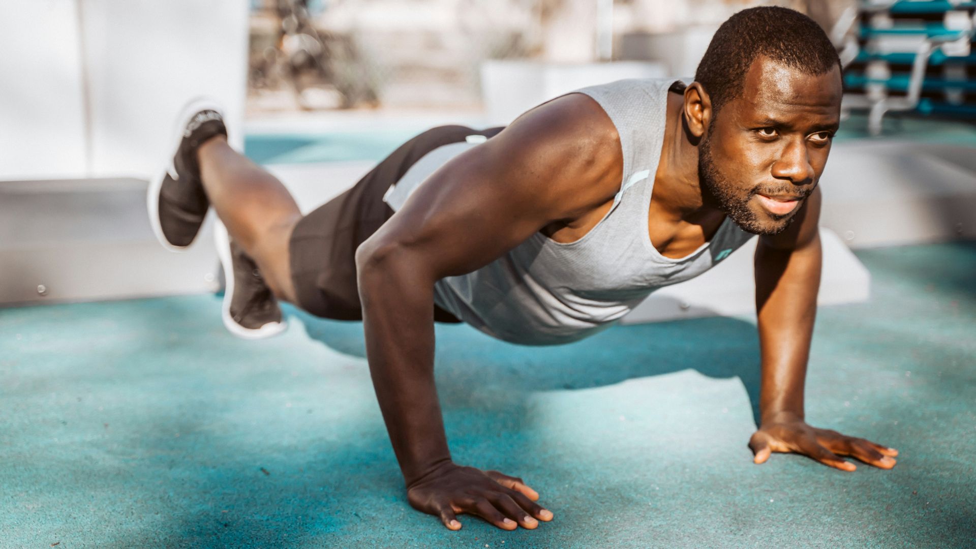 man in white tank top and gray shorts sitting on blue floor