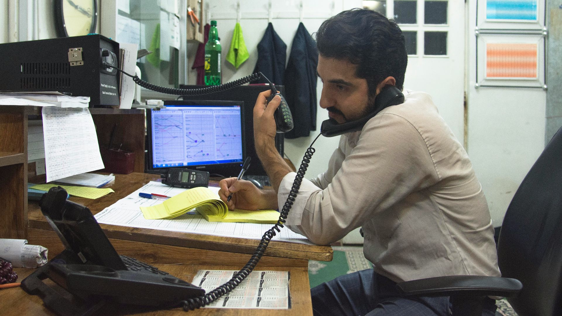 a man sitting at a desk talking on a phone