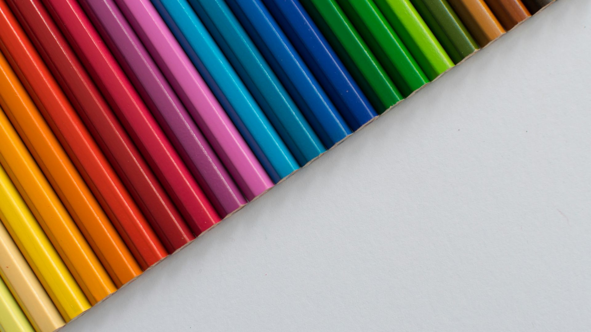 A row of colored pencils sitting next to each other