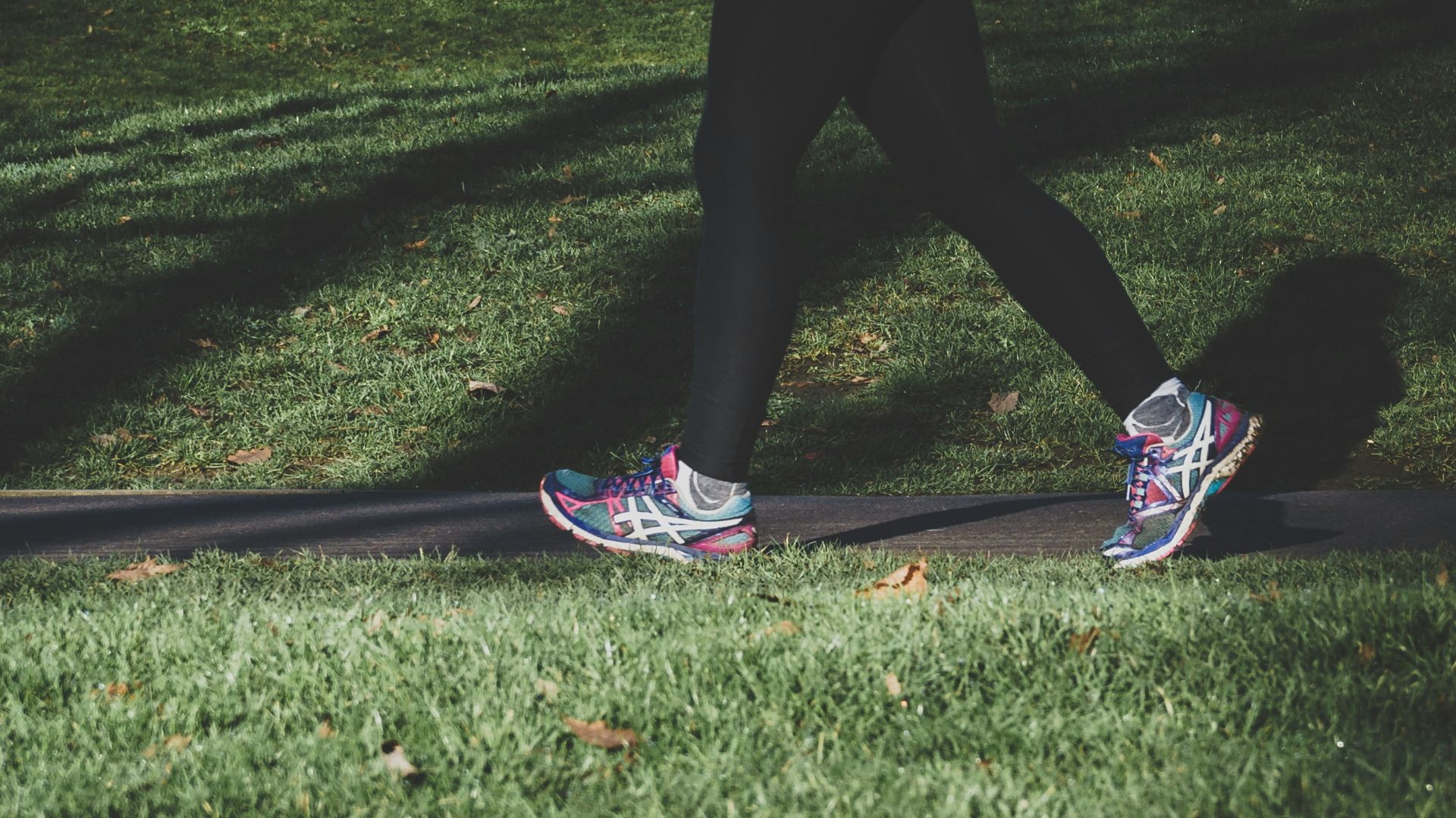 shallow focus photography of person walking on road between grass