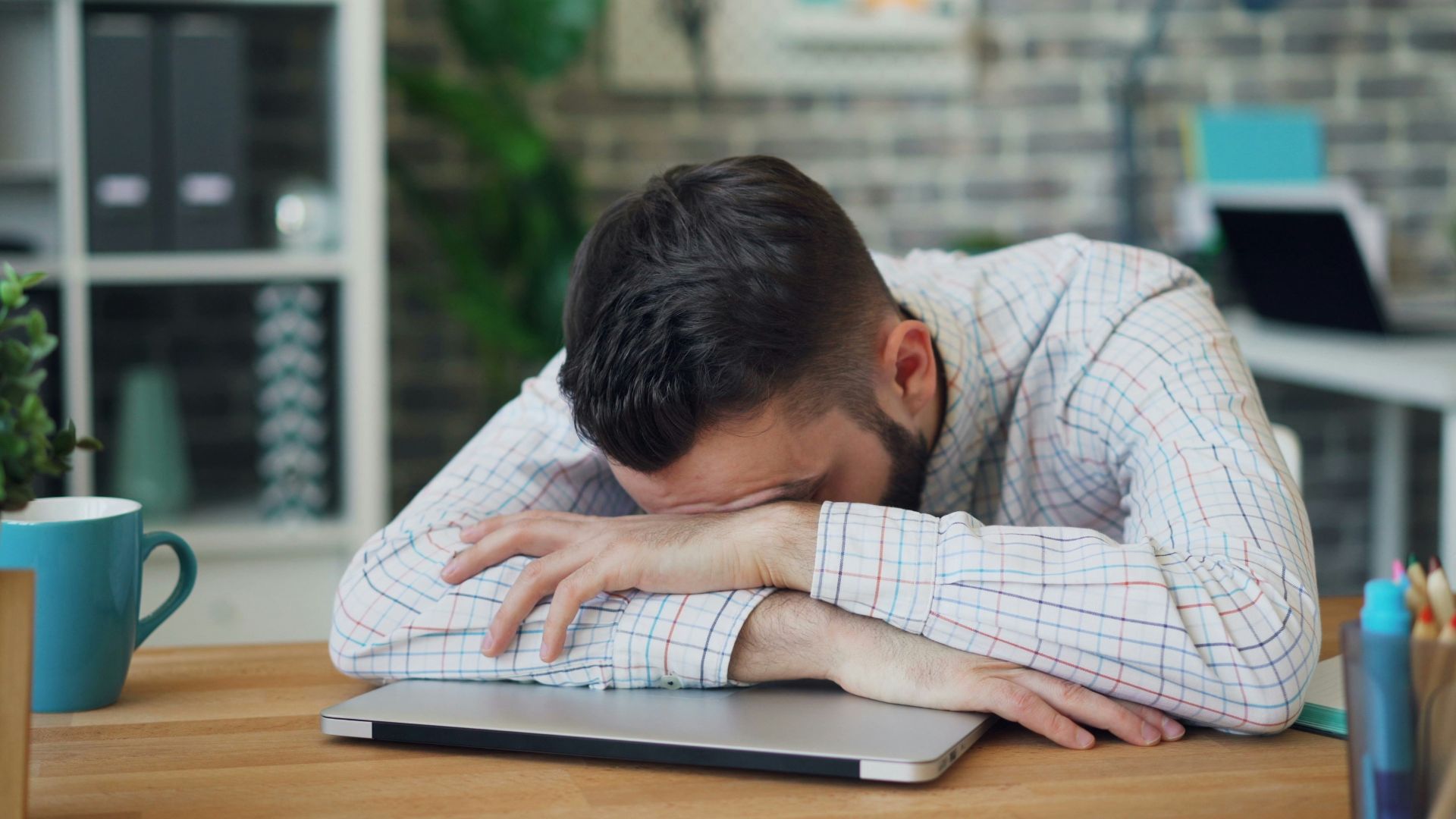 a man sitting at a desk with his head in his hands