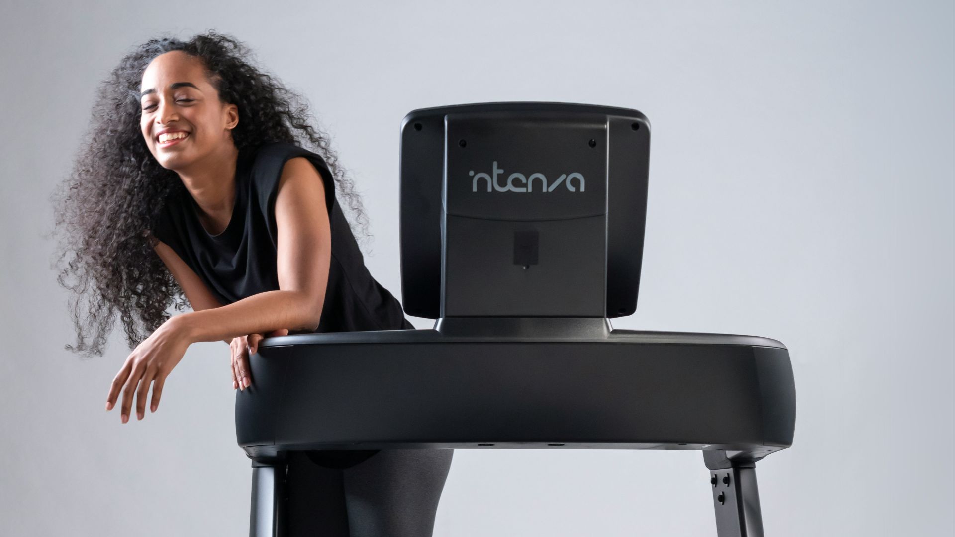 a woman standing on a treadmill with a laptop on top of it