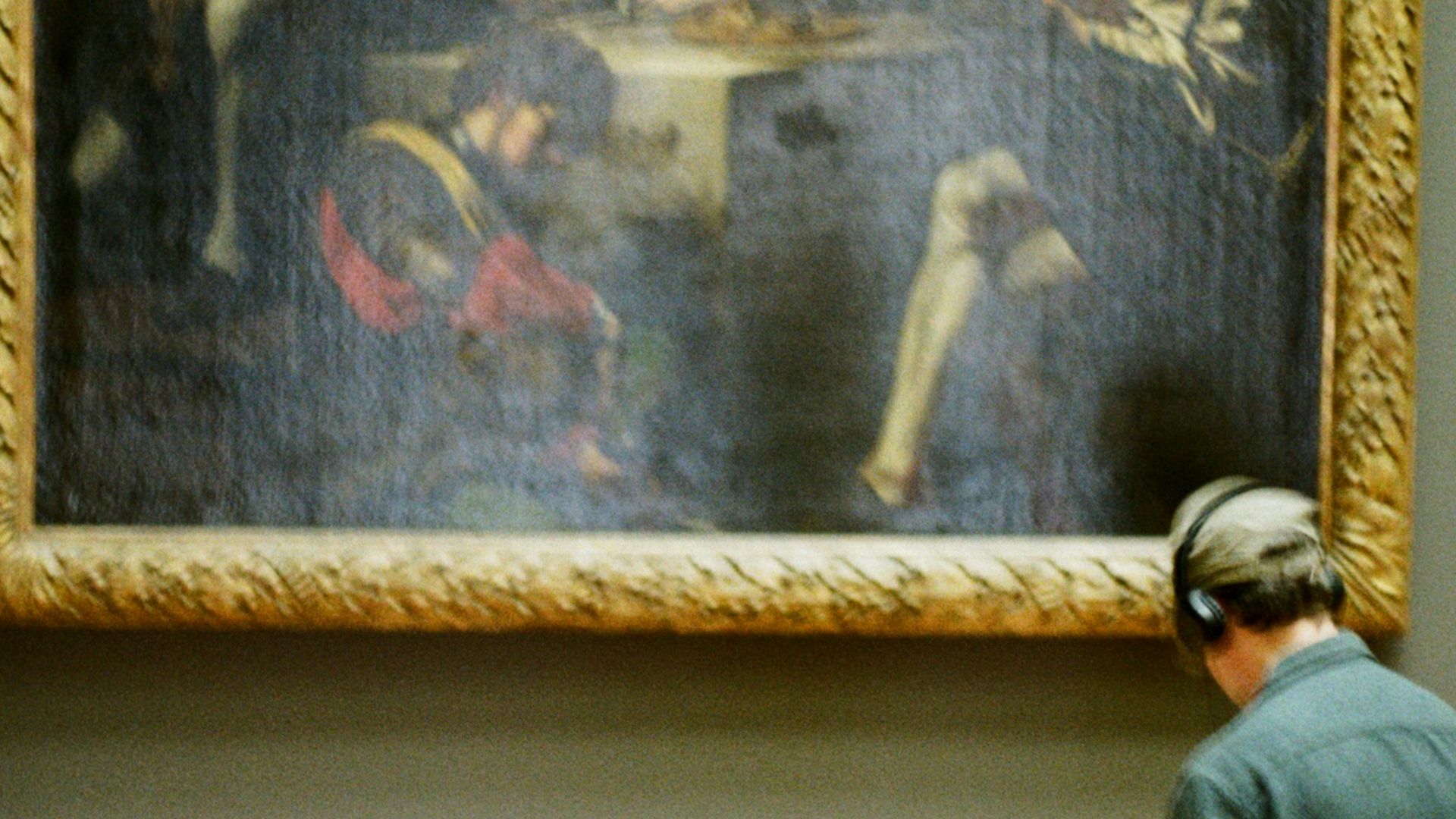 Person sits in front of a painting in a museum.