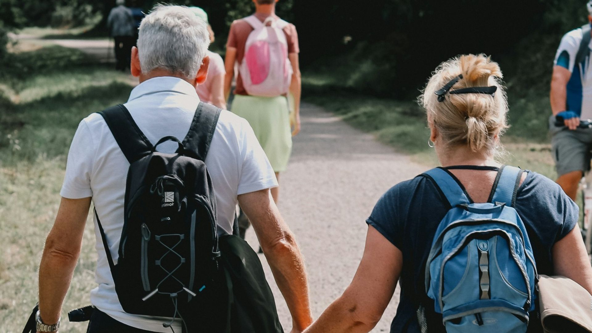 Couple holds hands while walking down a path.