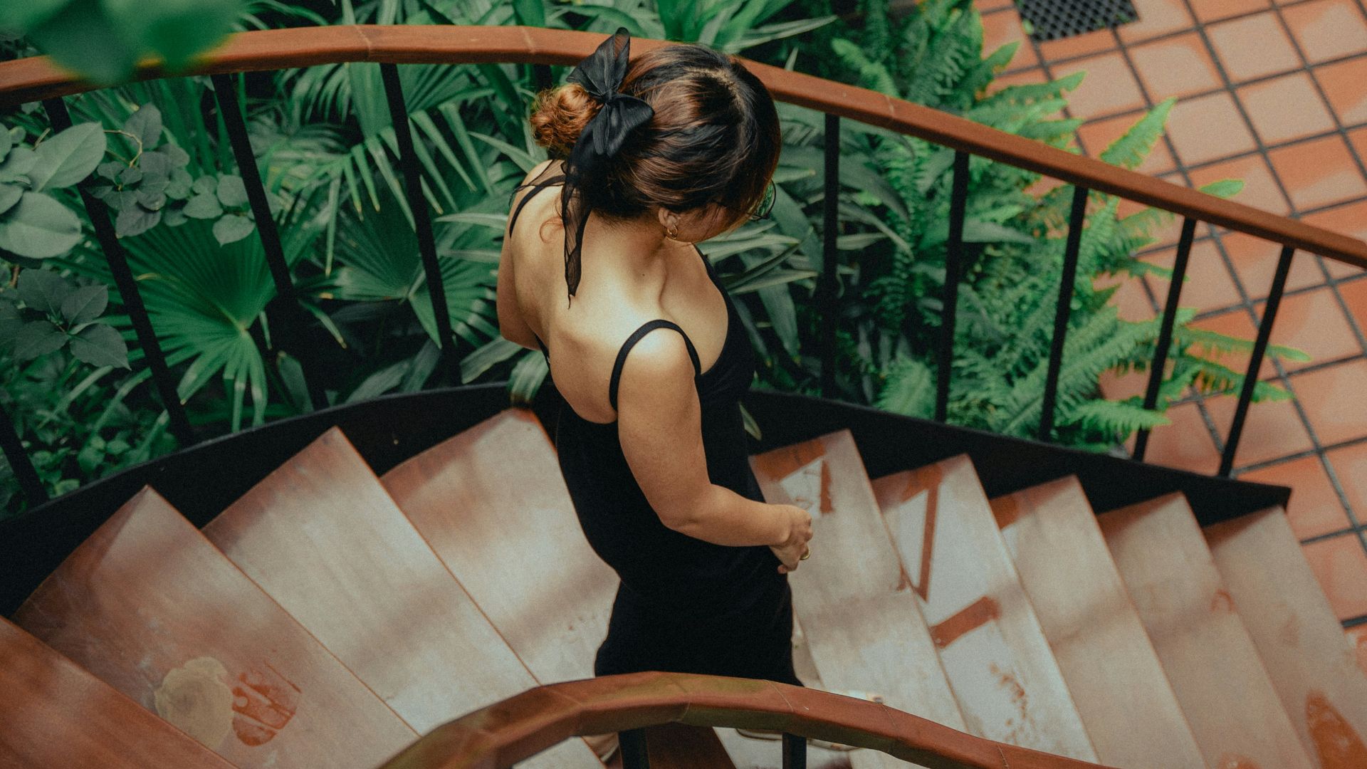 a woman in a black dress walking down a set of stairs