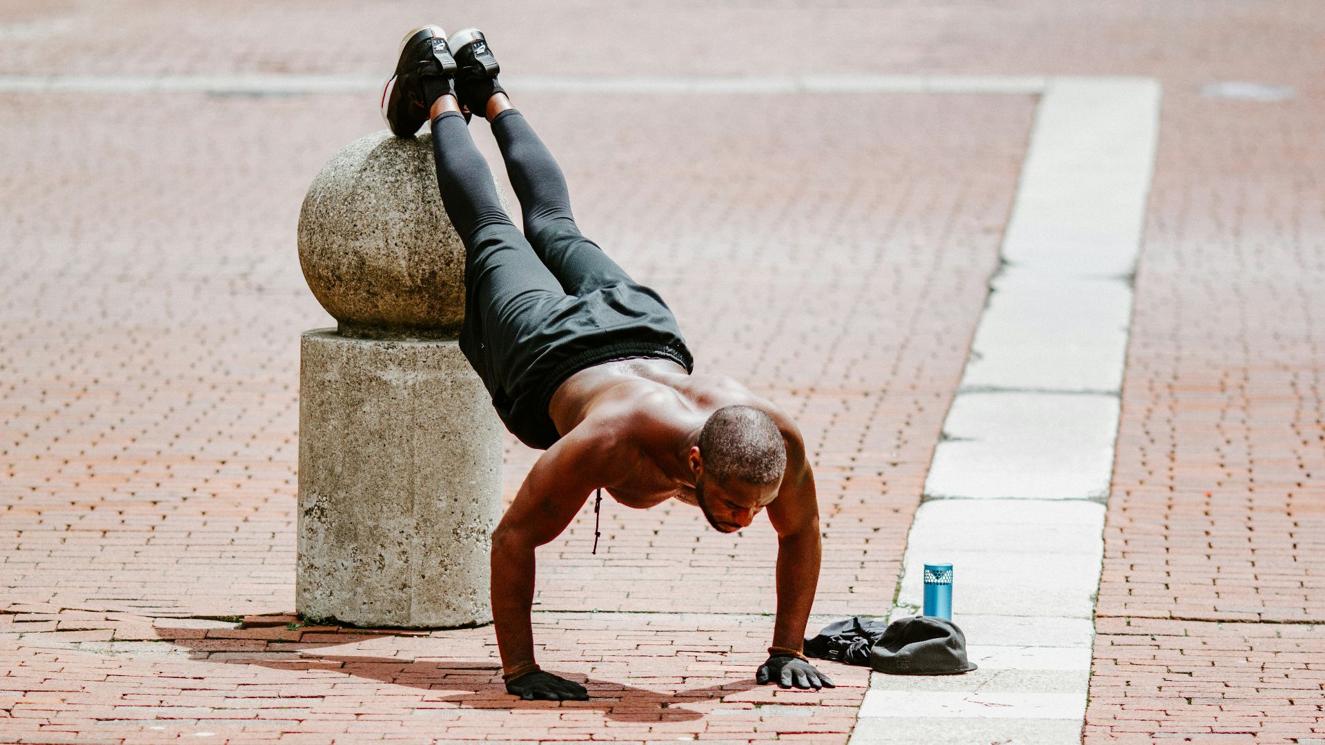 man in black tank top and black shorts lying on brown concrete floor during daytime