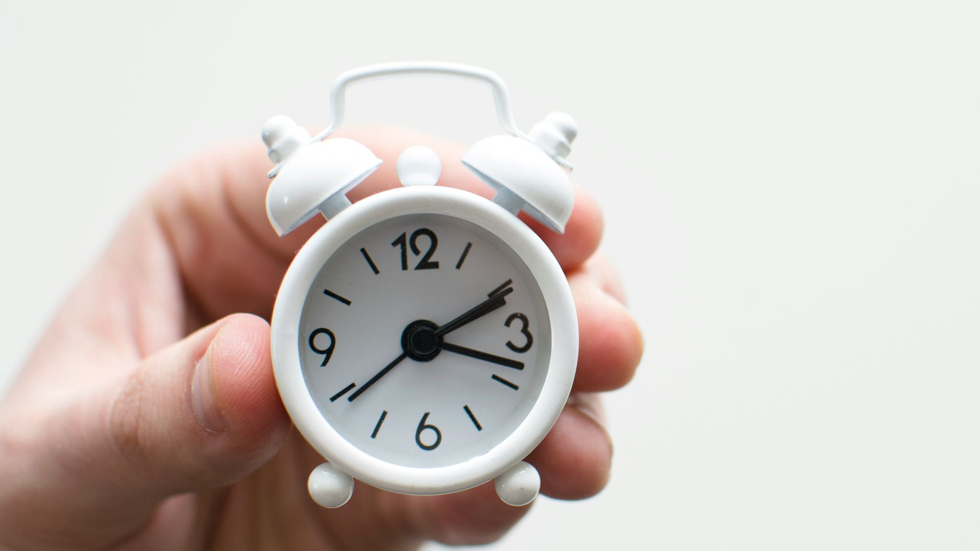 person holding white mini bell alarmclock