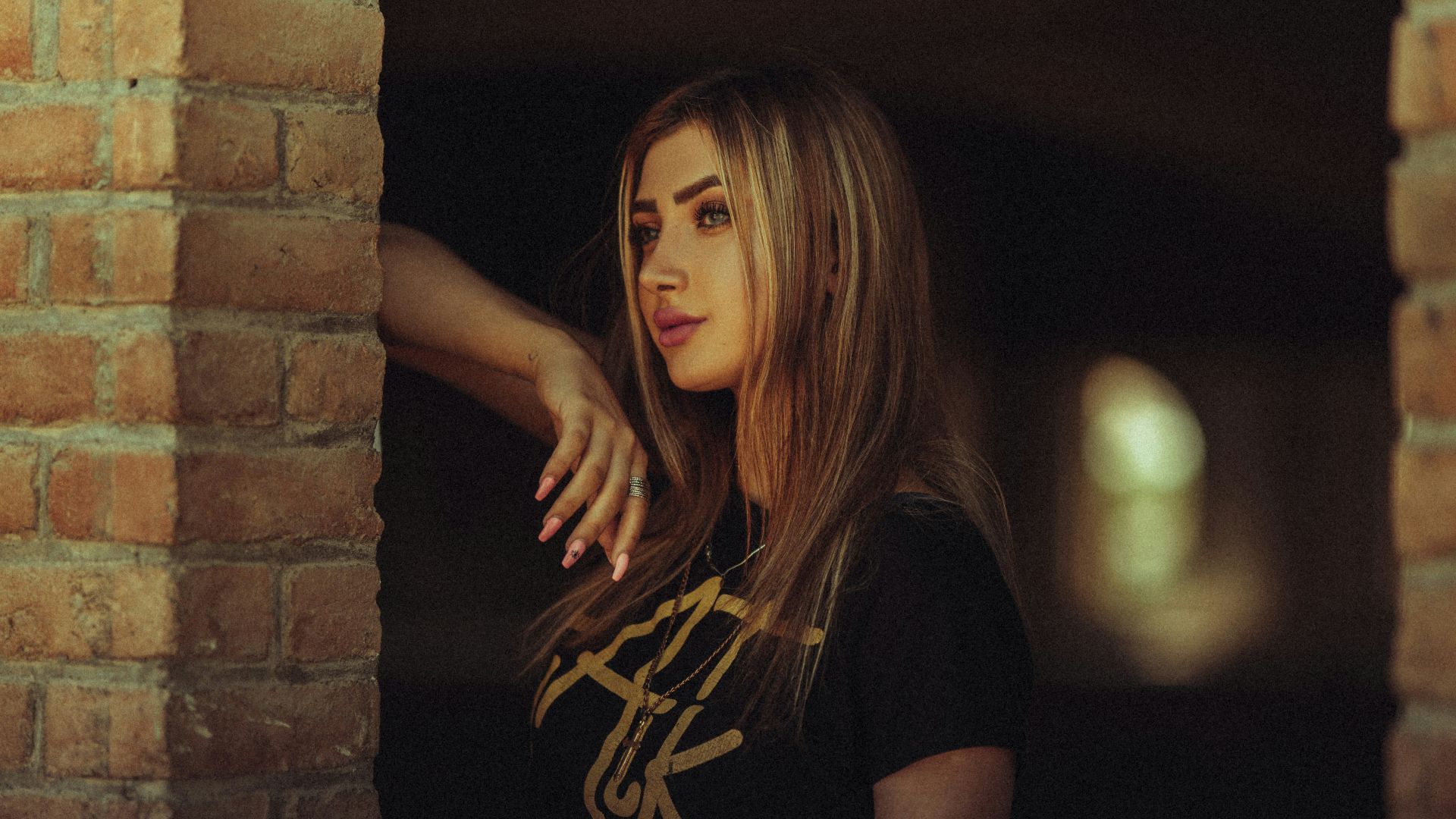 a woman standing in front of a brick wall
