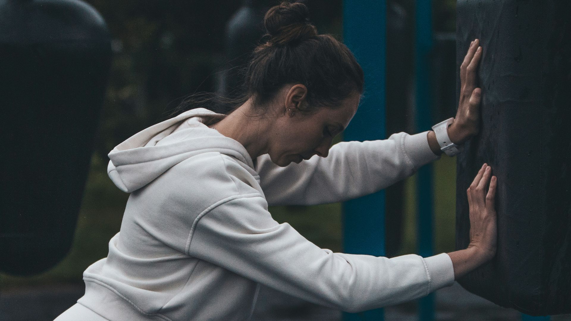 A woman stretches at an outdoor boxing gym.