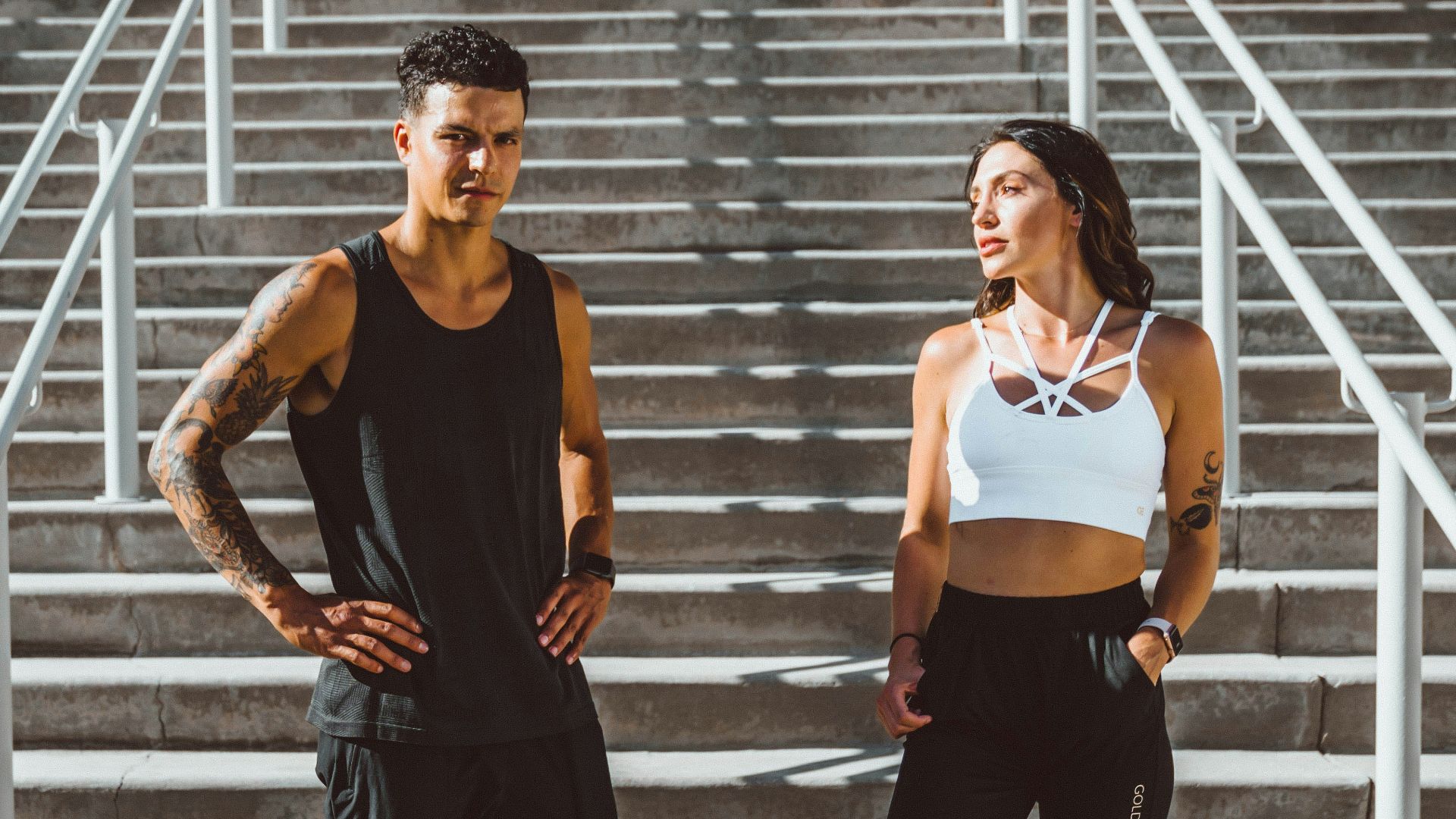 woman in black tank top and black pants standing on gray concrete stairs