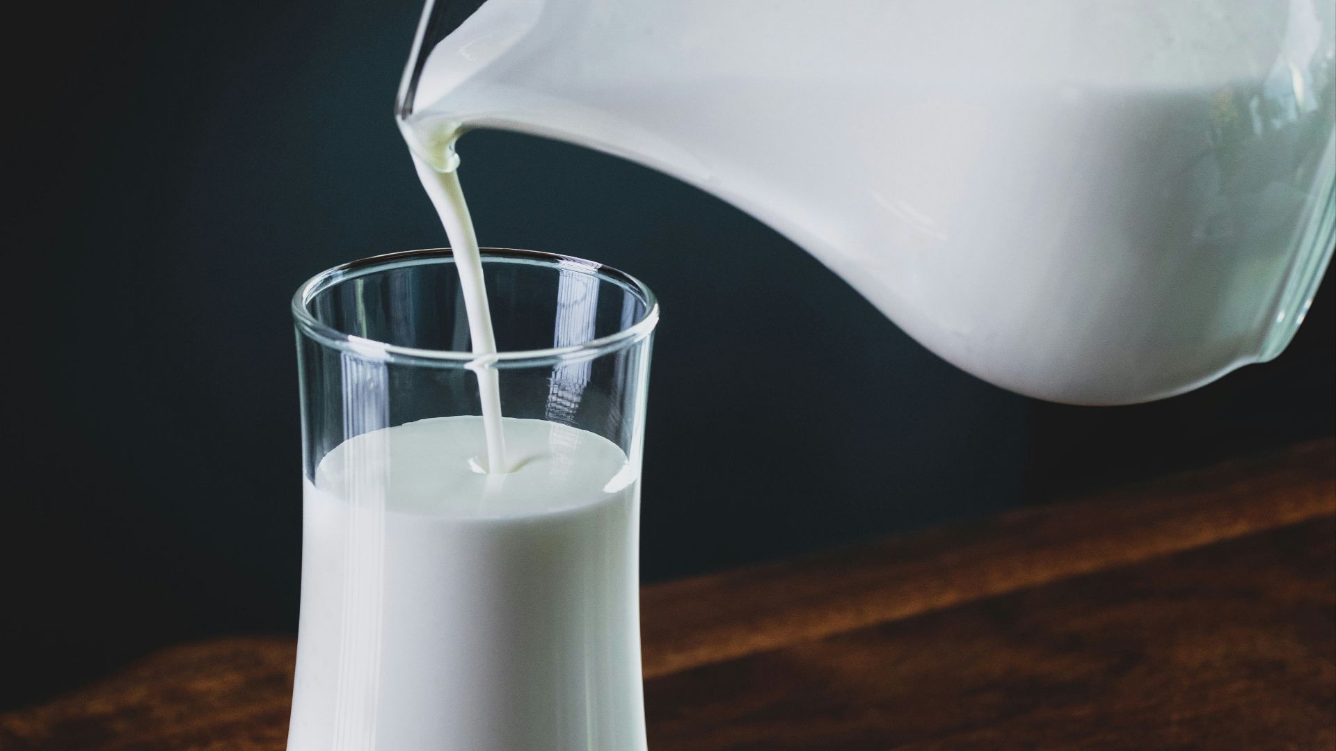 person pours milk into glass