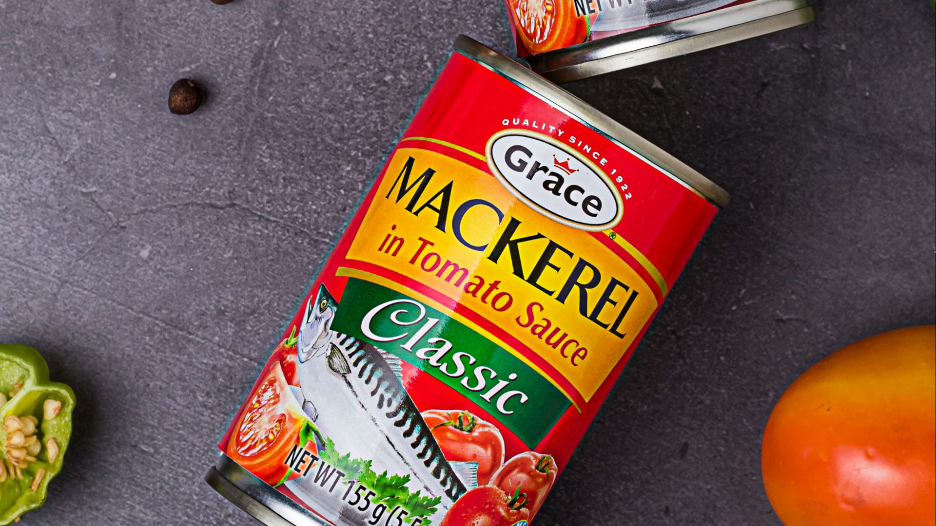 three cans of mackerel on a table next to some vegetables