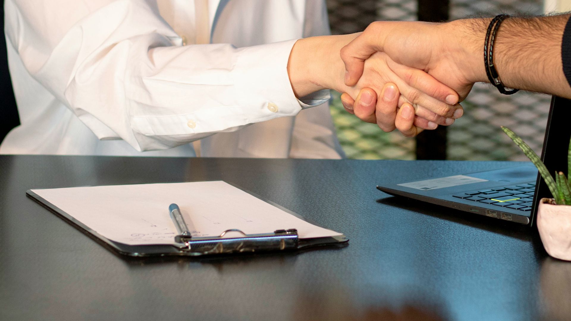 a man and a woman shaking hands in front of a laptop